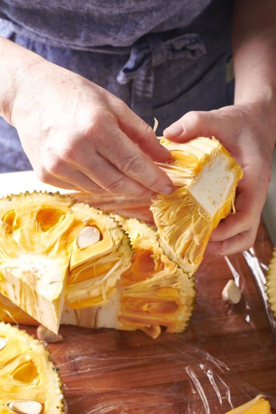 Woman holding a piece of jackfruit.