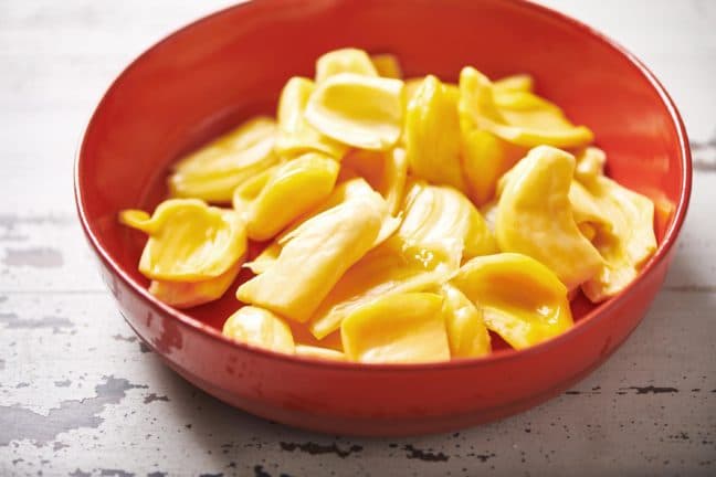 Red bowl of jackfruit pods.