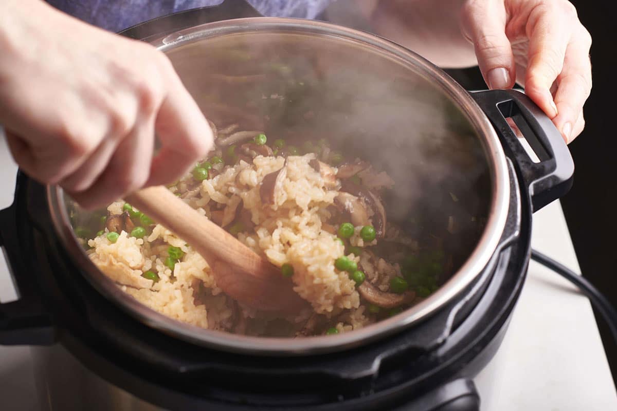 Woman stirring an Instant Pot of Mushroom Risotto.