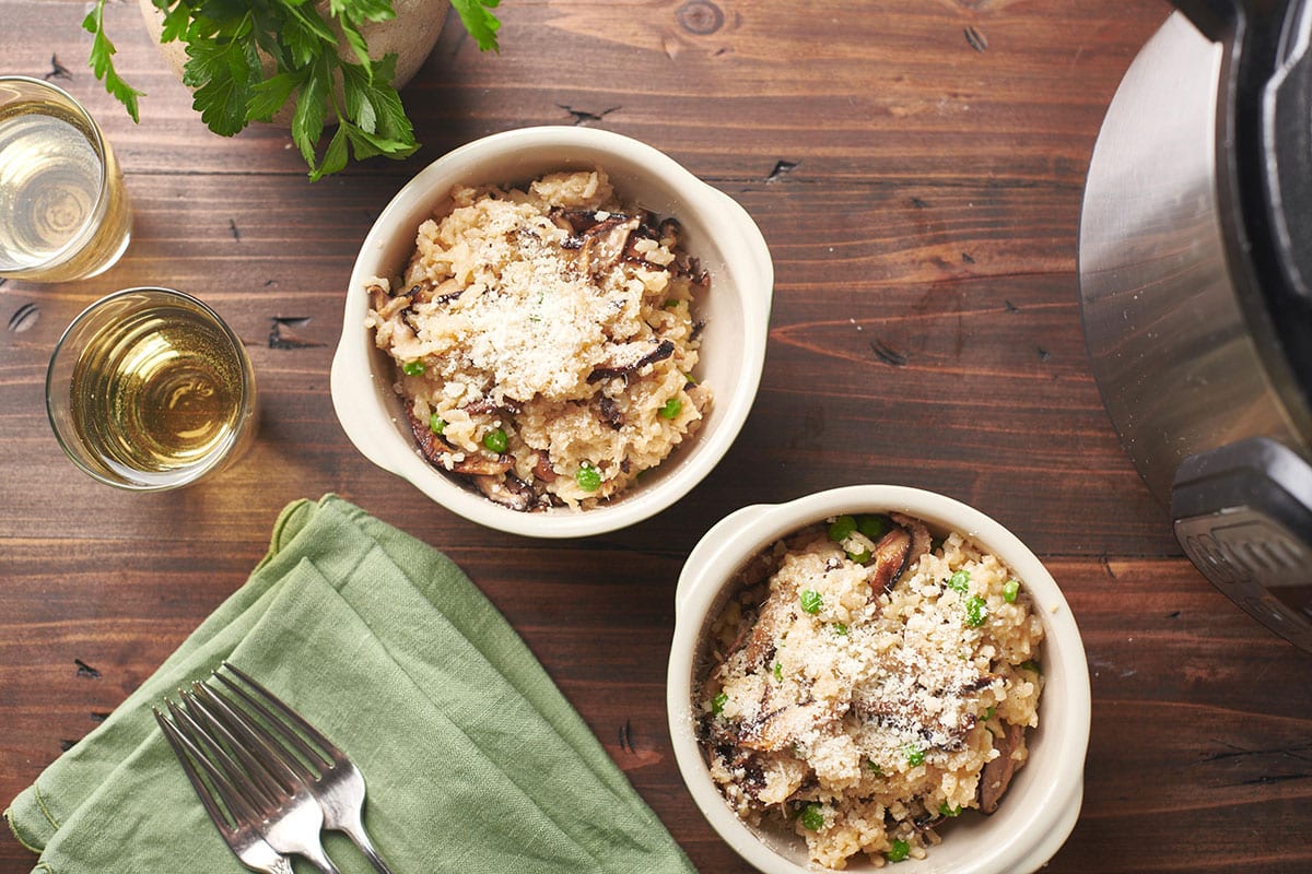 Small bowls of Mushroom Risotto on table with napkins, drinks, and forks.