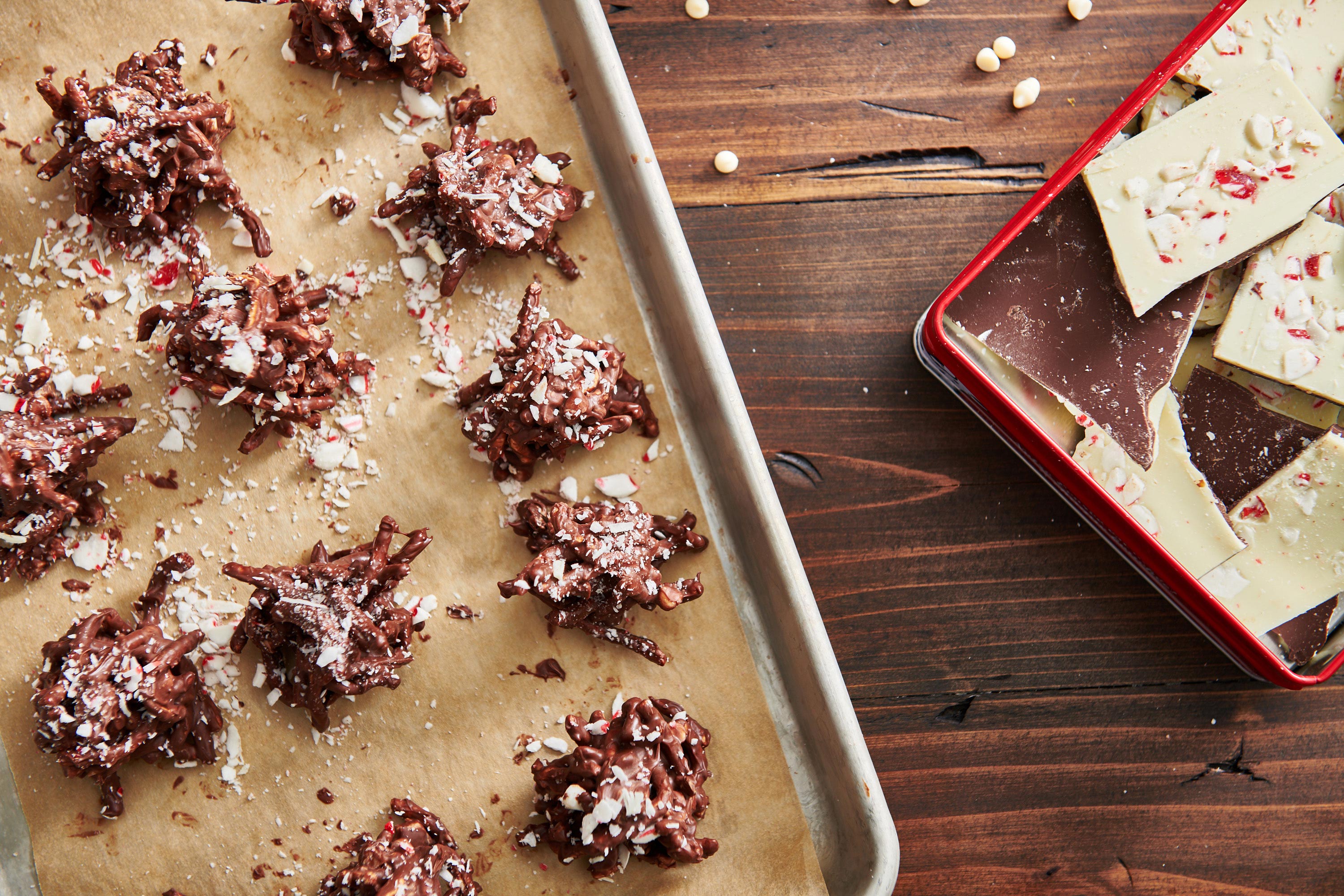Baking sheet of Peppermint Bark Haystack Cookies on a table with chocolate.