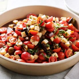 Tomato salad with mozzarella and basil in serving dish on table.