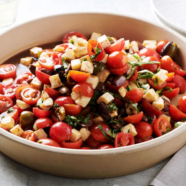 Tomato salad with mozzarella and basil in serving dish on table.