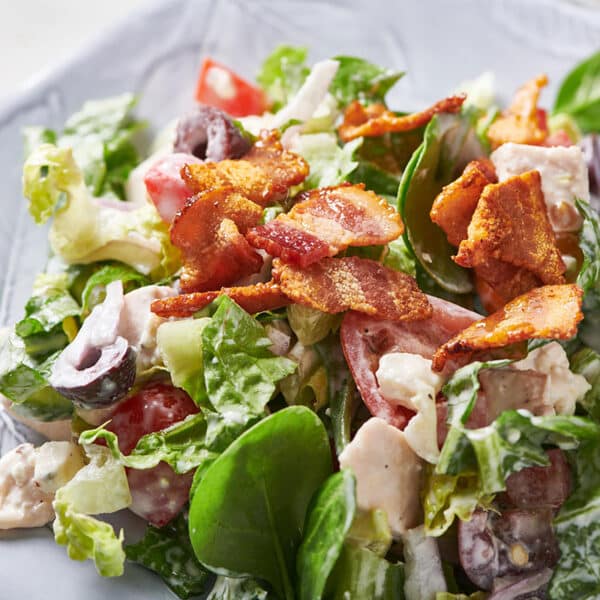 Chopped salad with chicken and blue cheese on white plate.