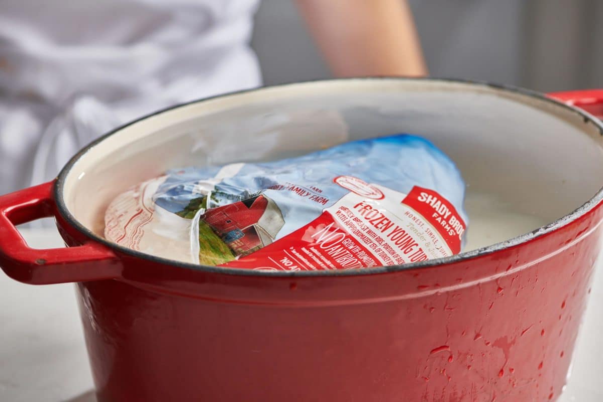 Wrapped, frozen turkey in a pan of water.