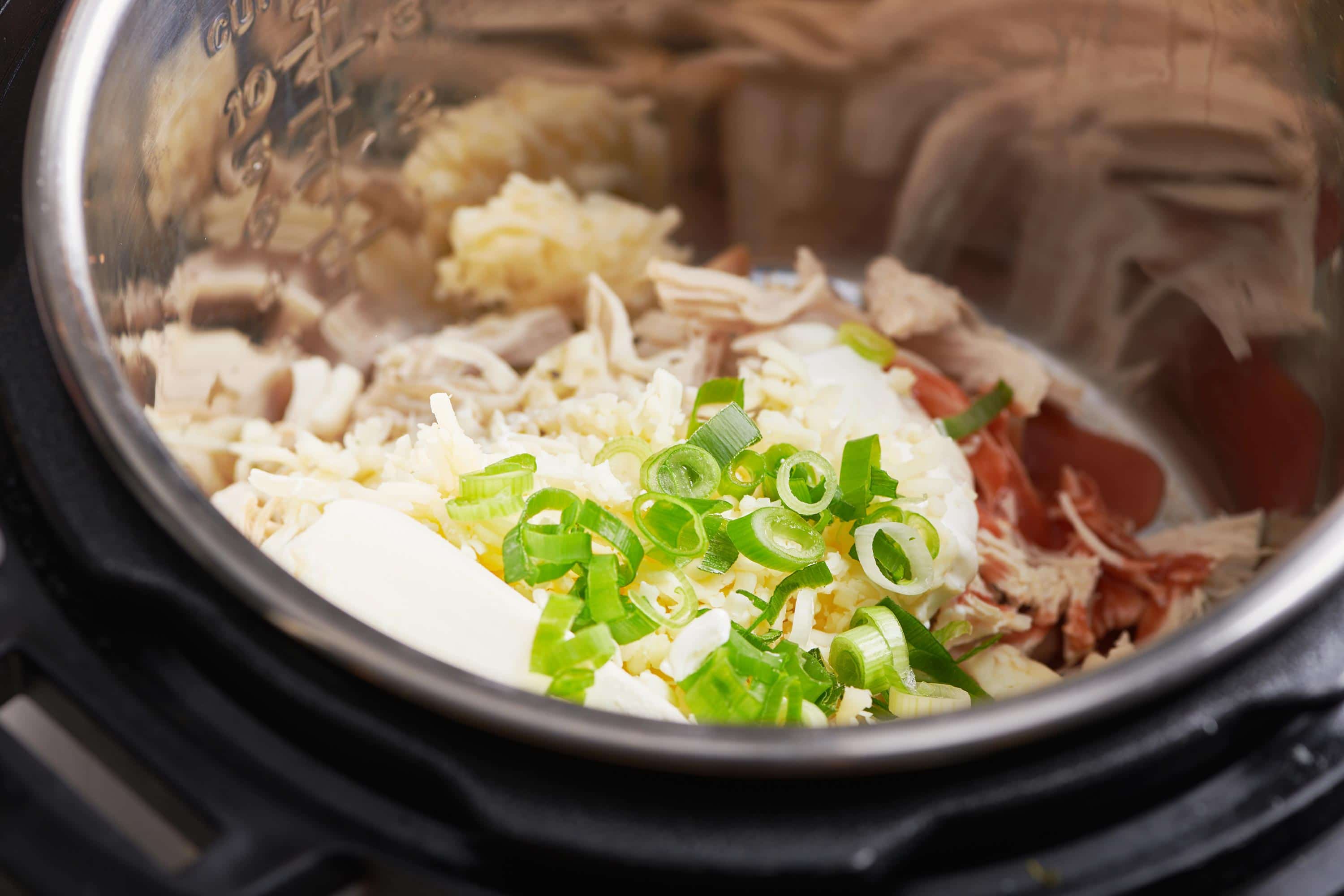 Scallions, cream cheese, and other ingredients in an Instant Pot.