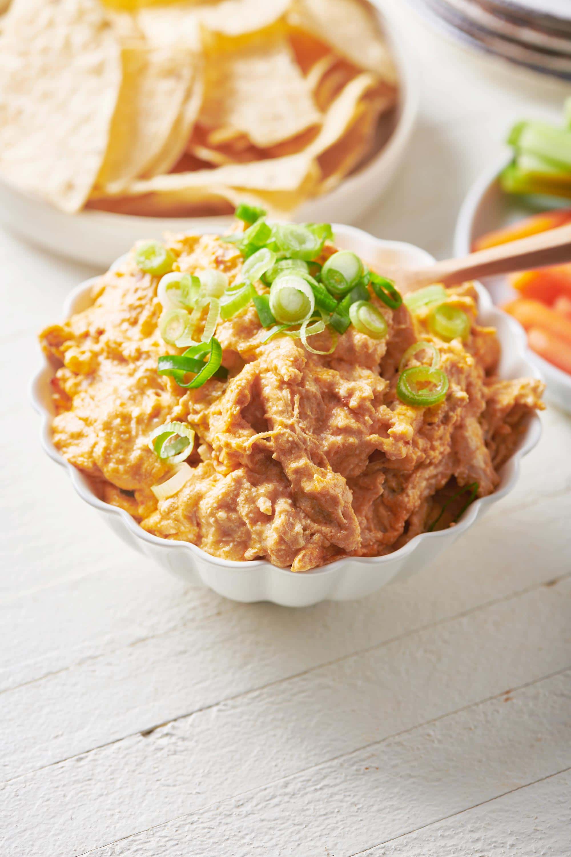Spoon in a small white bowl of Buffalo Chicken Dip.