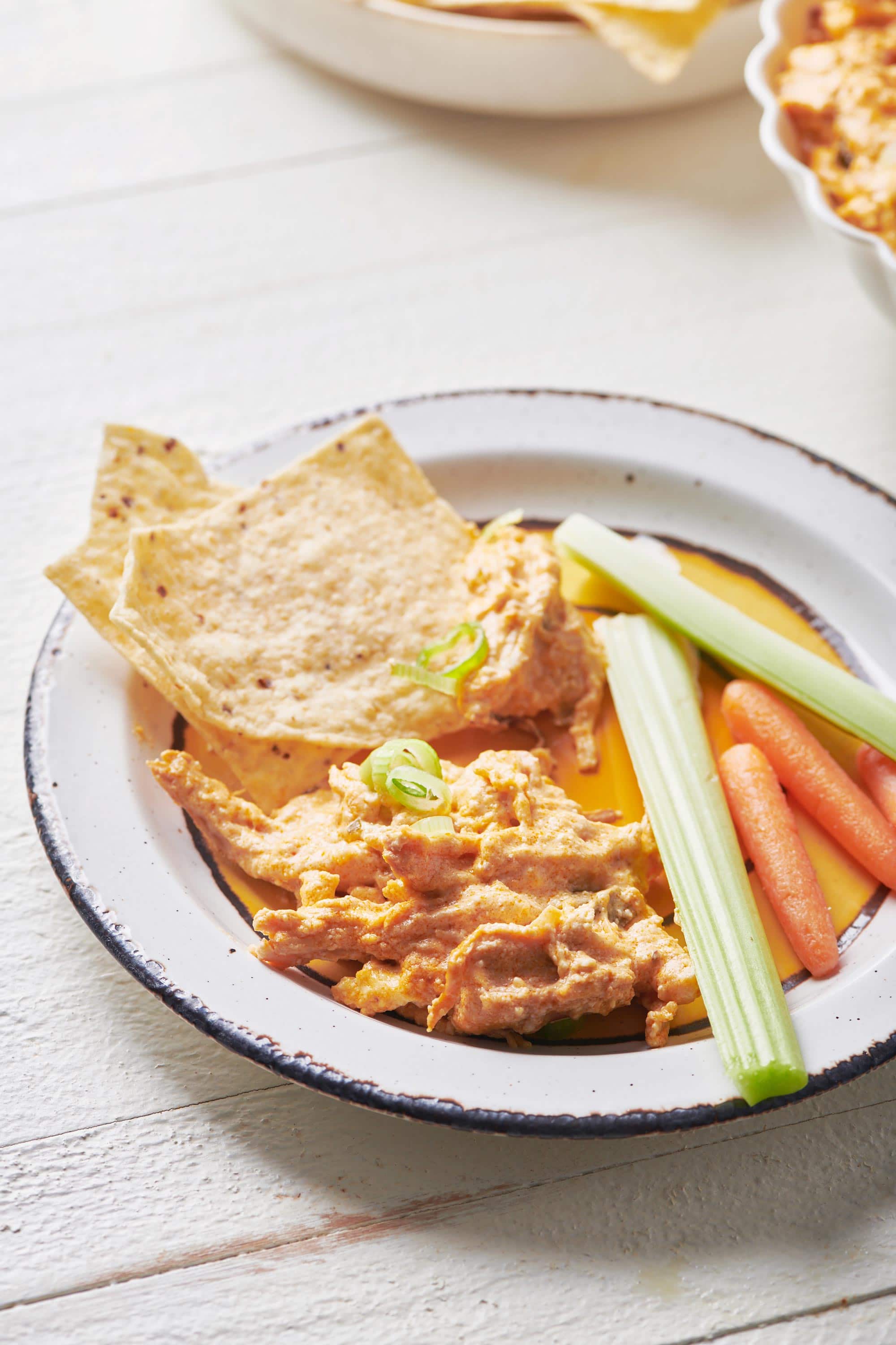 Buffalo Chicken Dip on a plate with chips and vegetables.