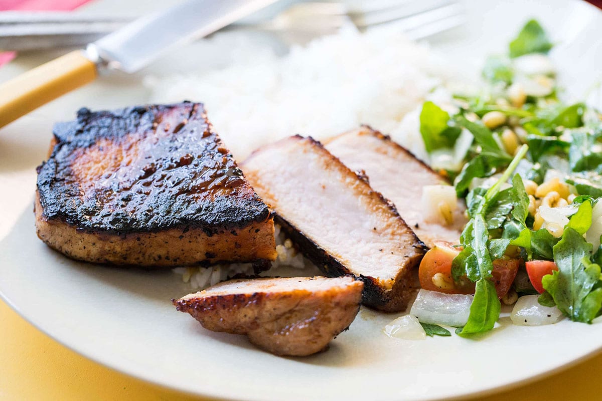 Sliced Korean Pork Chop with rice and salad on a plate.