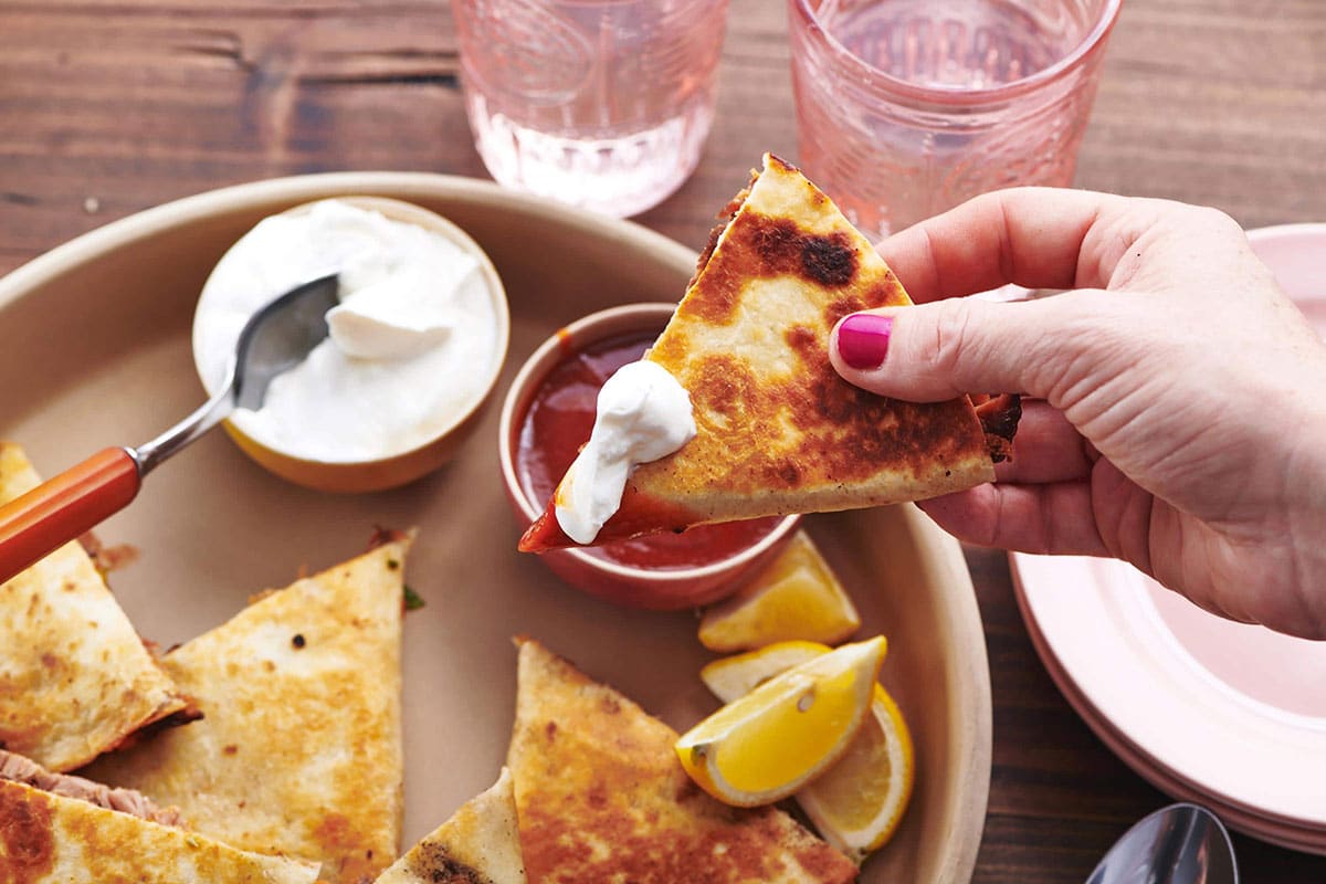 Pulled Pork Quesadilla dipped in barbecue sauce and sour cream.