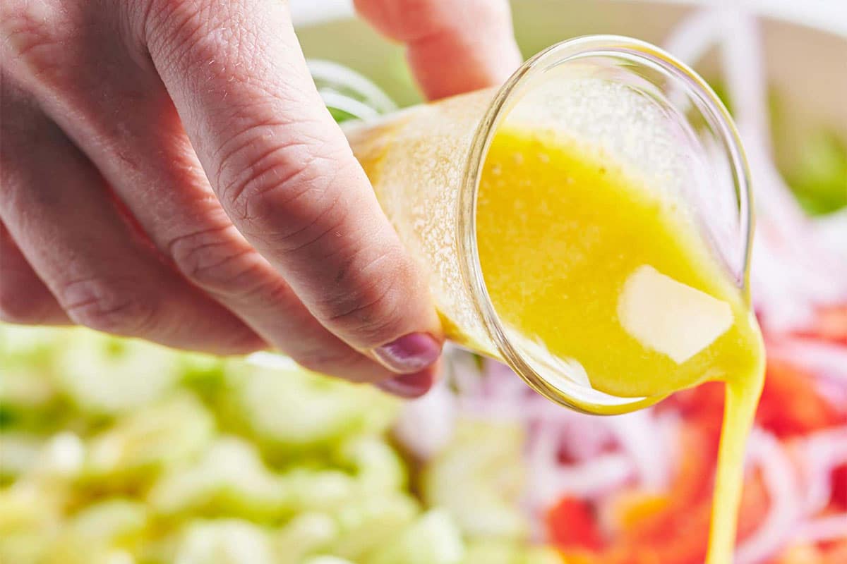 Woman pouring dressing onto a Romaine Salad with Queso Fresco.