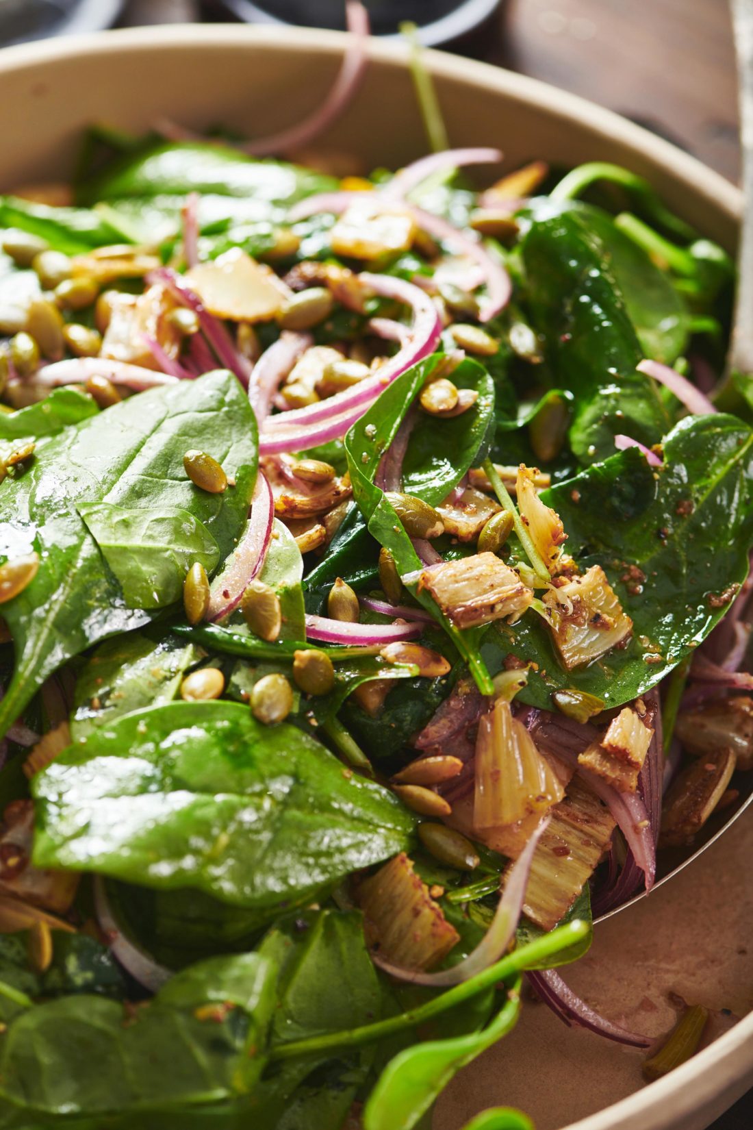Spinach Salad with Roasted Fennel topped with red onion and pepitas.