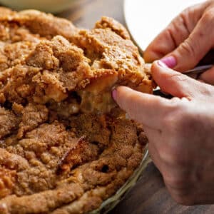 Serving apple pie with streusel topping from pie plate.