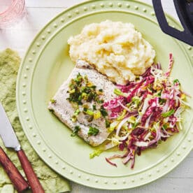 Yogurt-marinated fish on plate with potatoes and slaw.