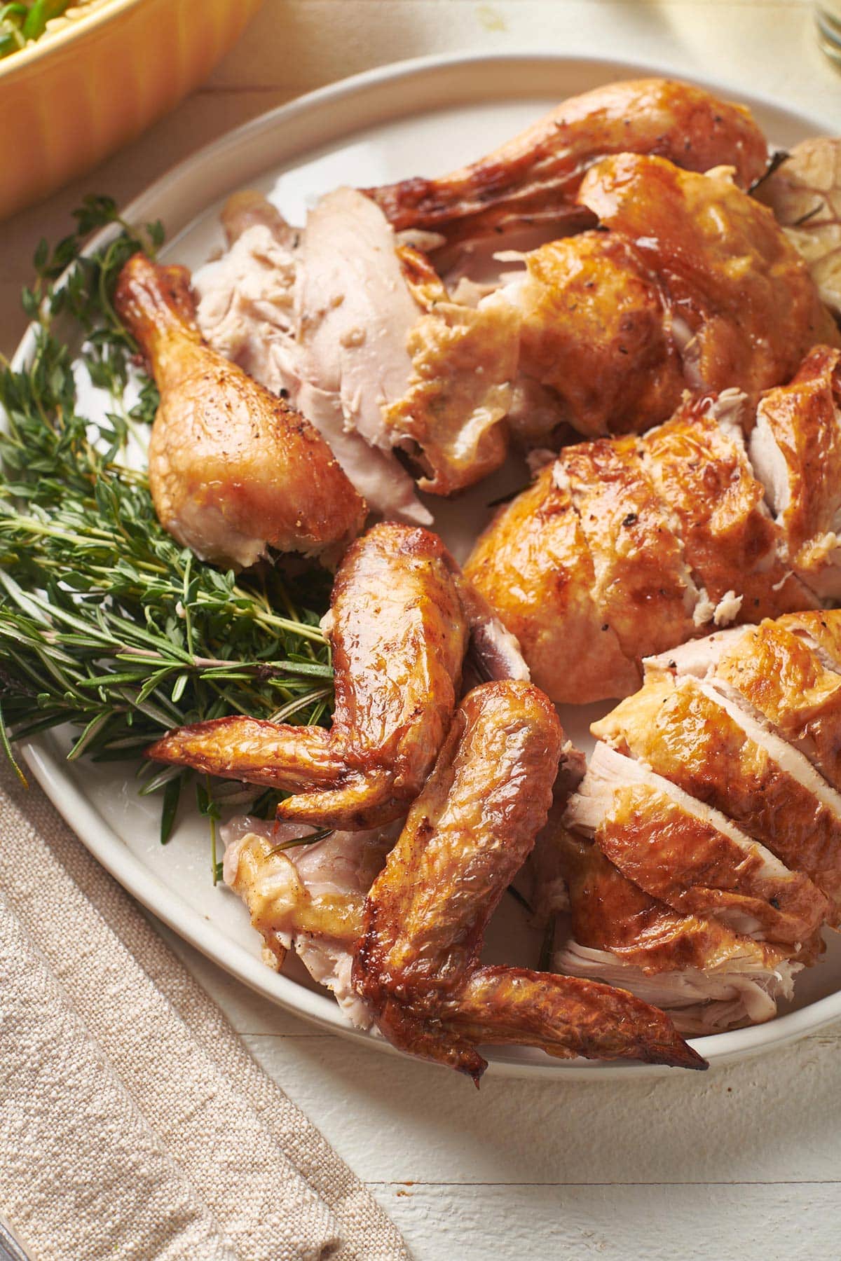 Roast chicken pieces on serving platter with fresh herbs.