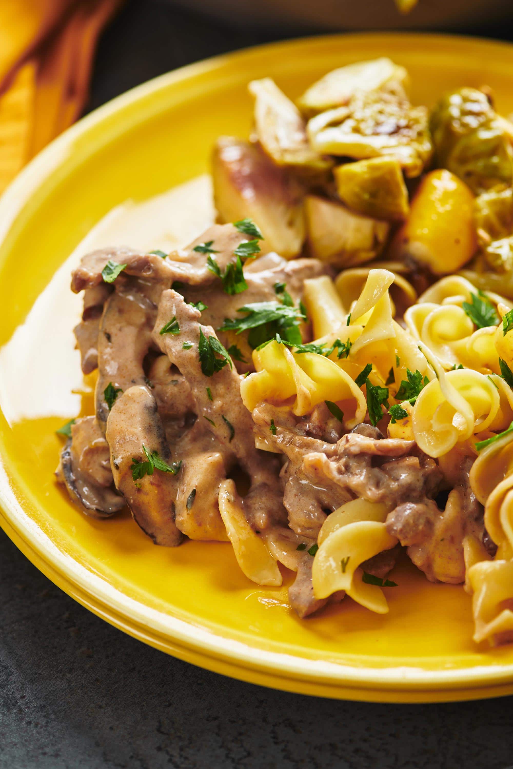 Beef Stroganoff and noddles on a yellow plate.