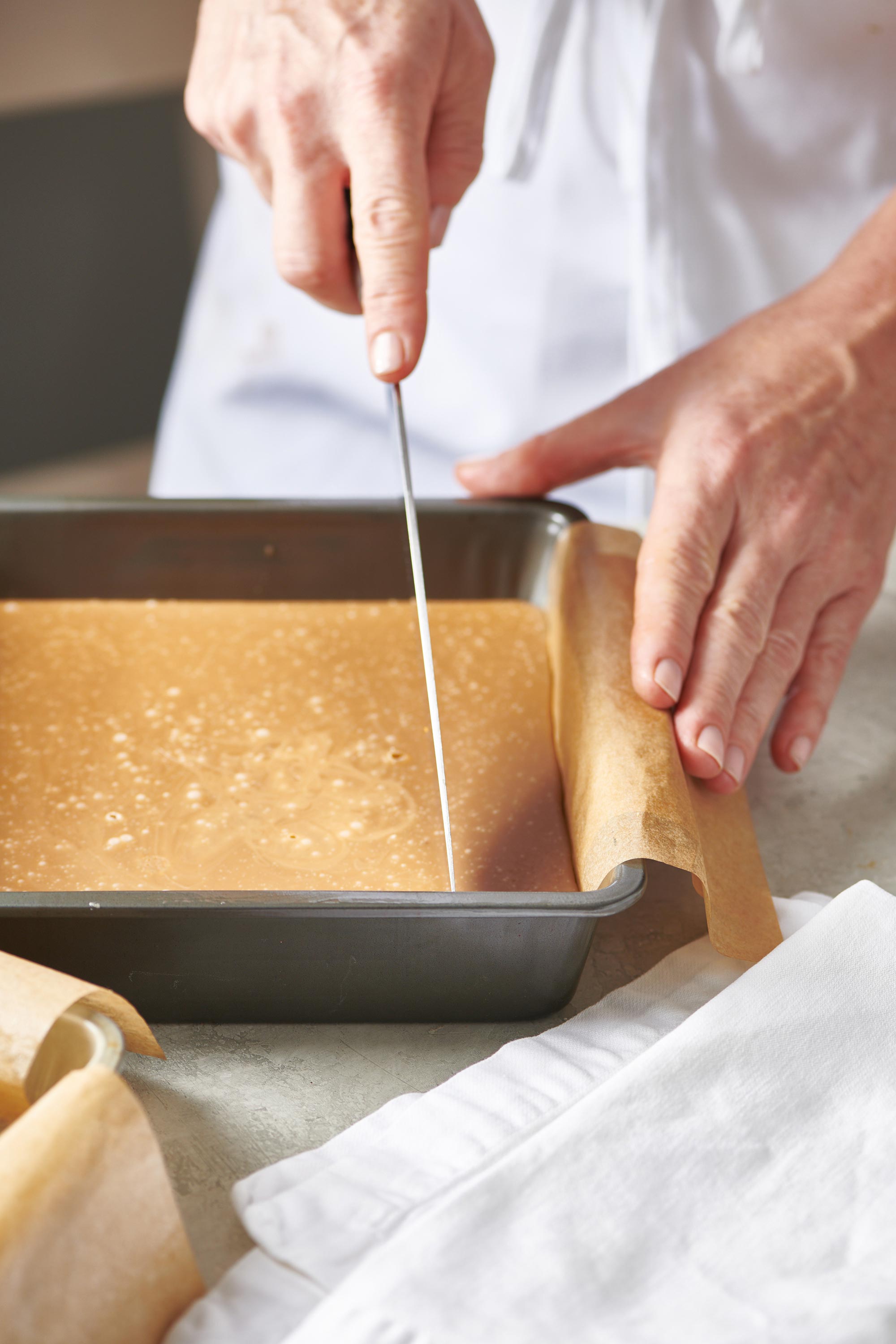 Woman slicing a pan of Brown Sugar Fudge.
