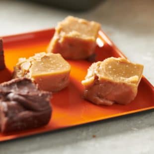Slices of Brown Sugar Fudge and other fudge on an orange plate.