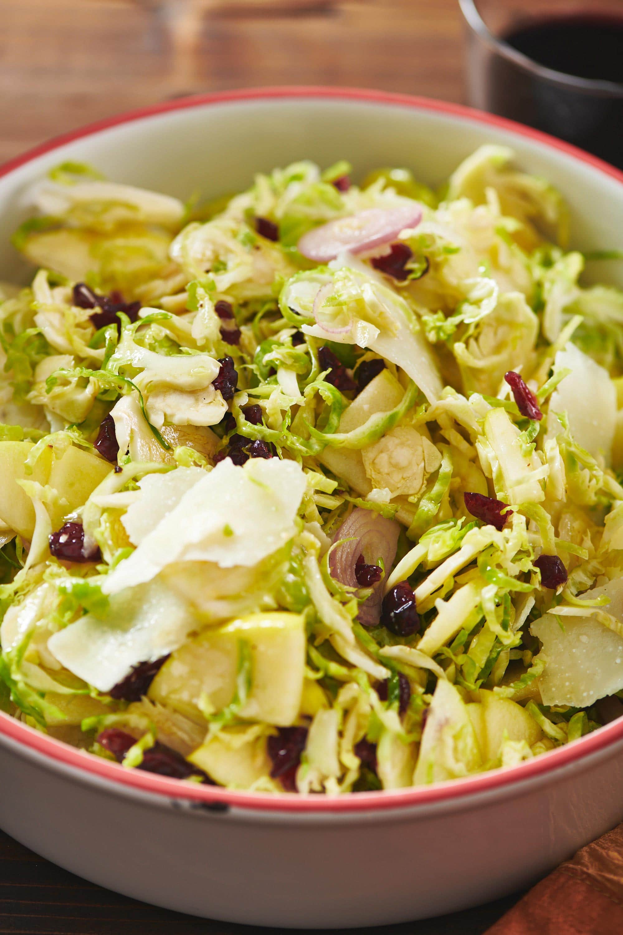 Bowl of Brussels Sprouts, Pecorino and Apple Salad on a wooden table.