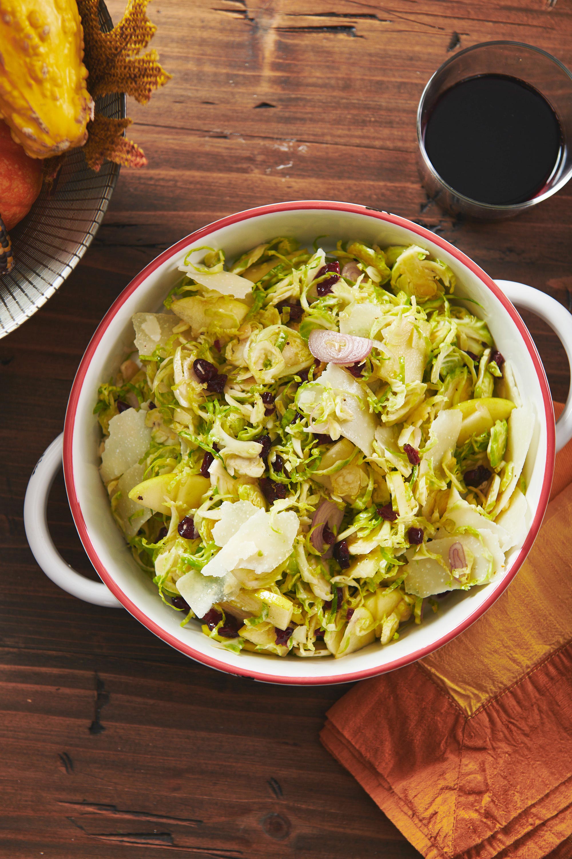 Red-rimmed white bowl of Brussels Sprouts, Pecorino and Apple Salad.