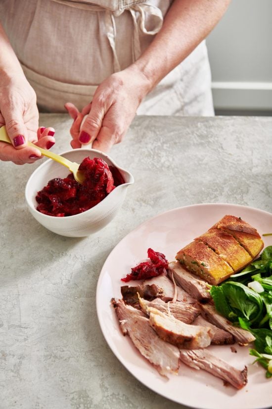 Woman scooping Cranberry Orange Sauce from a small bowl.