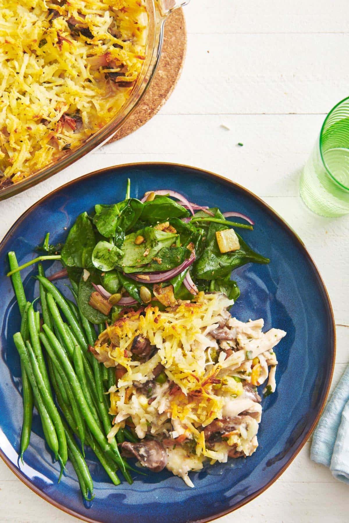 Hashbrown Chicken Vegetable Pot Pie Casserole on a blue plate with salad and green beans.