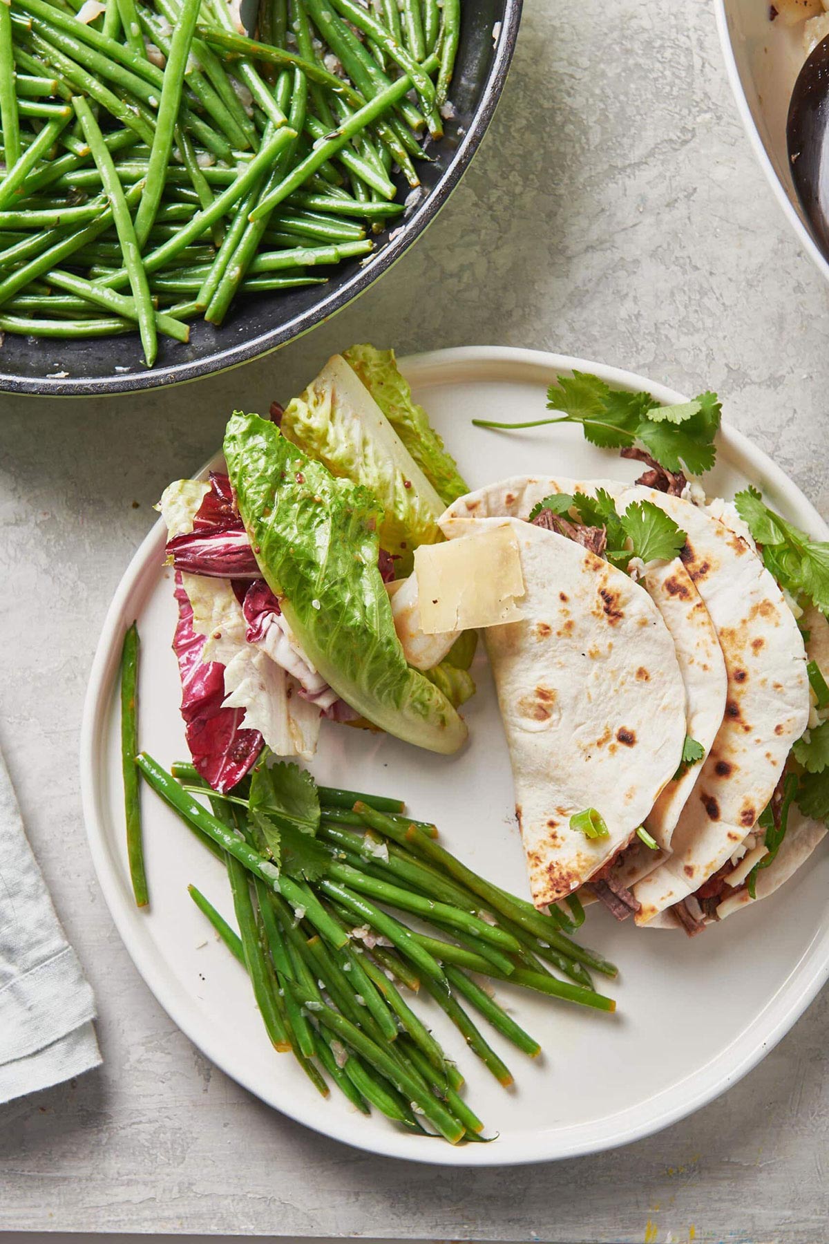 Mixed Lettuce Salad with Mustard Vinaigrette on a plate with beans and tacos.
