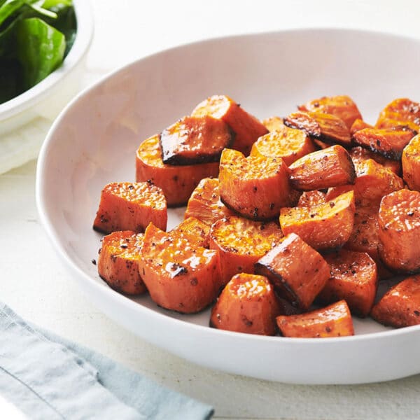 Butter roasted sweet potatoes in white serving dish on table.