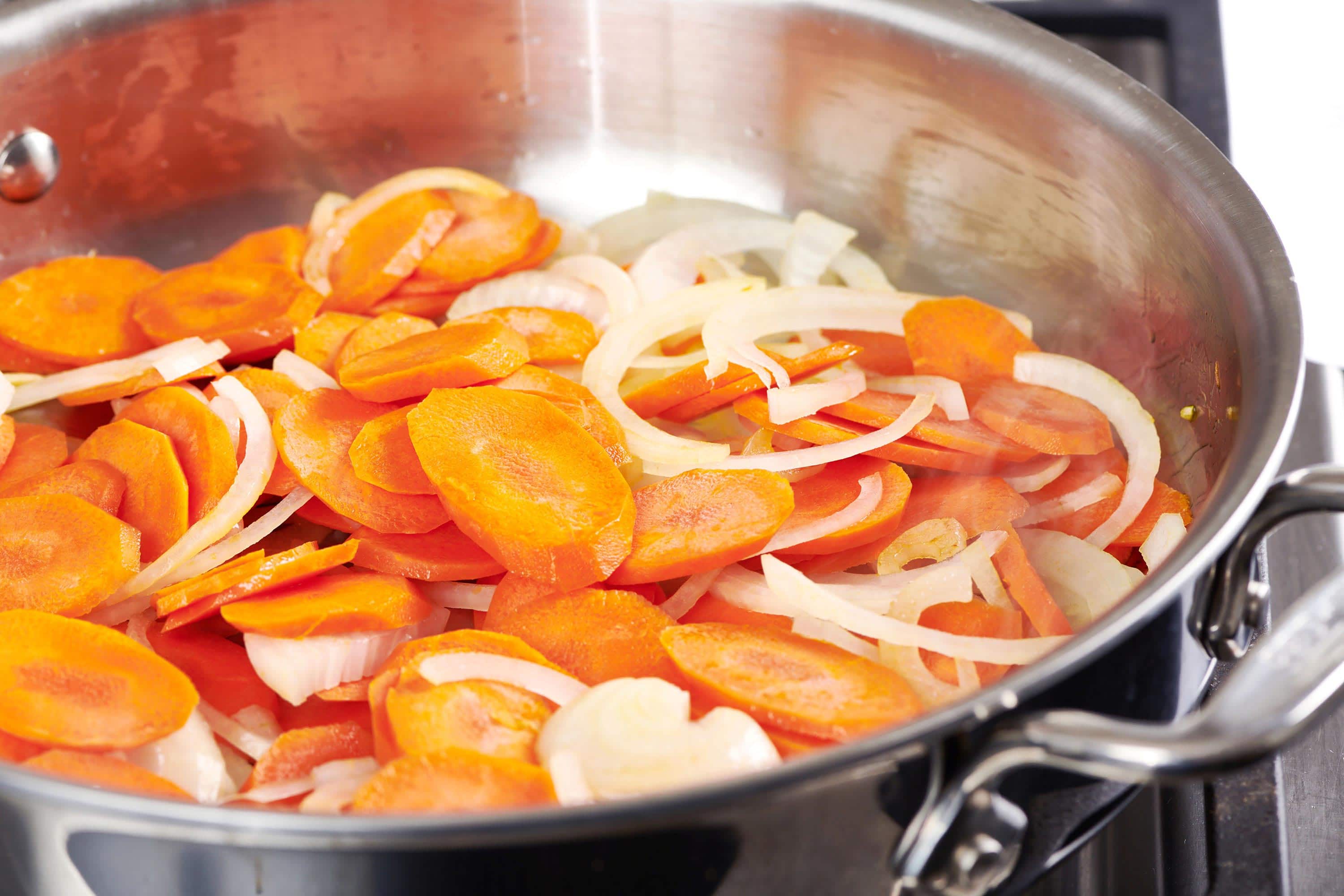 Sliced carrots and onions in a pan.