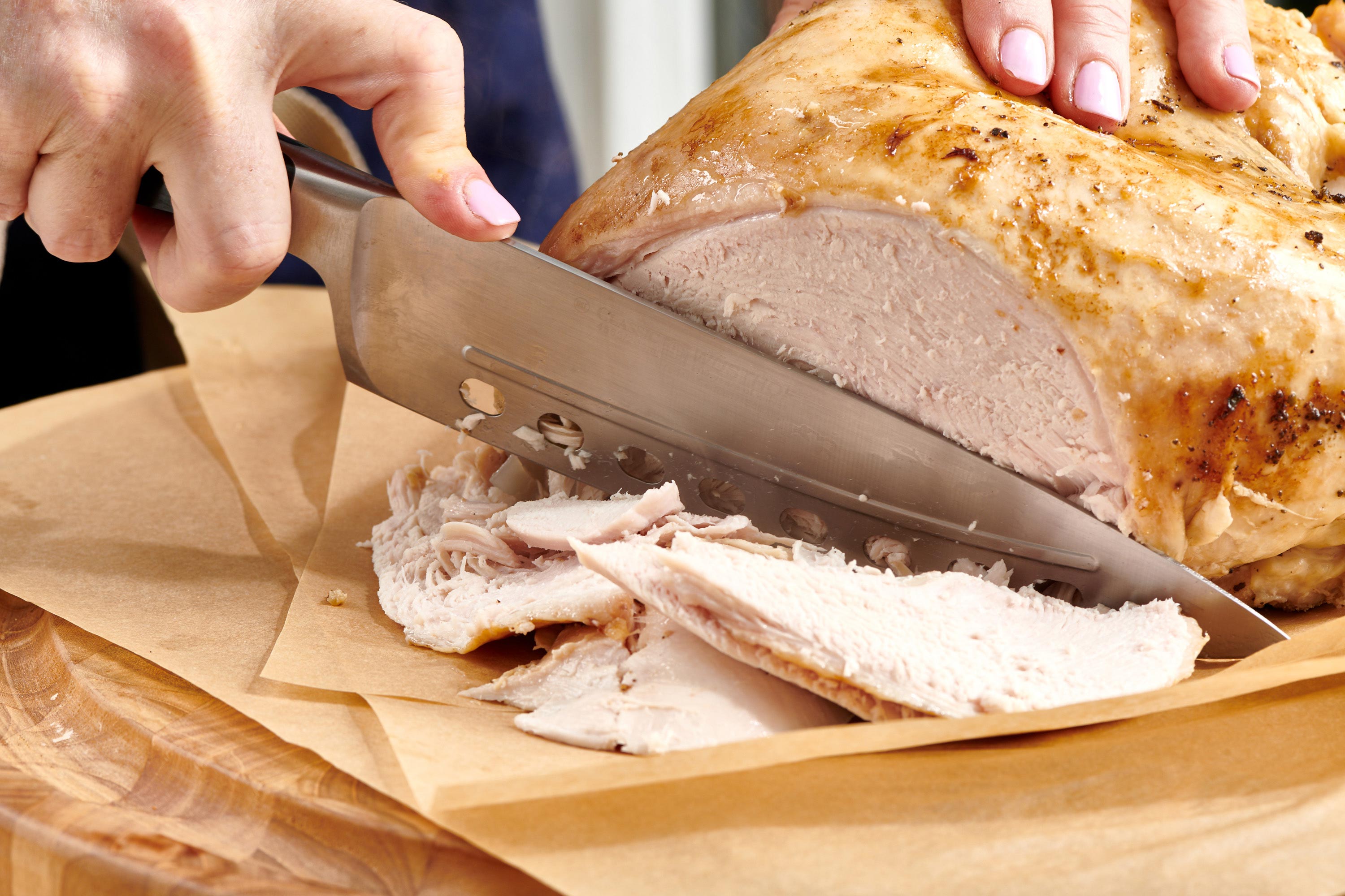 Slicing Slow Cooker Turkey Breast with knife on cutting board.