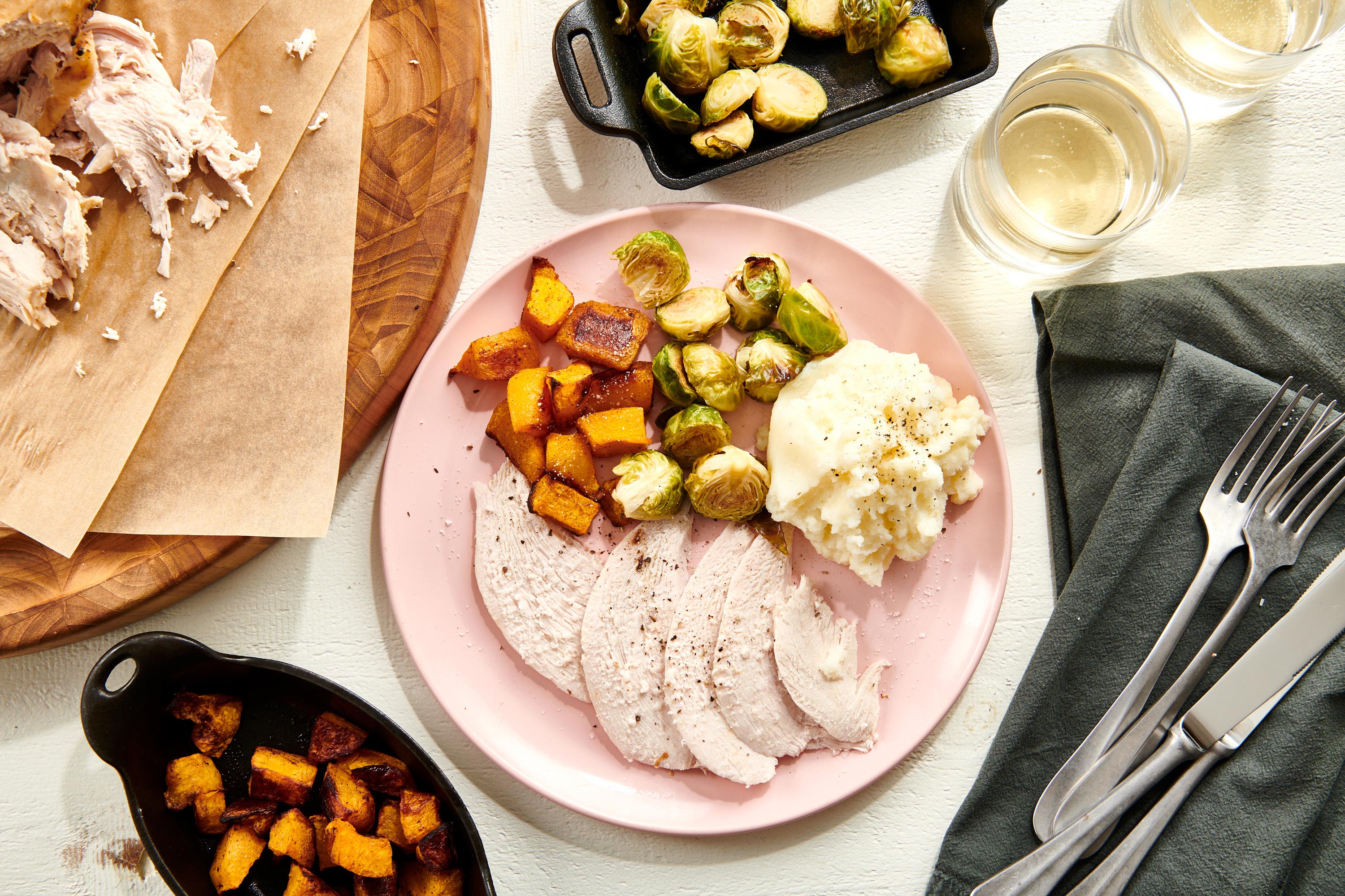 Pink plate with brussels sprouts, sweet potato, mashed potatoes, and Turkey Breast.