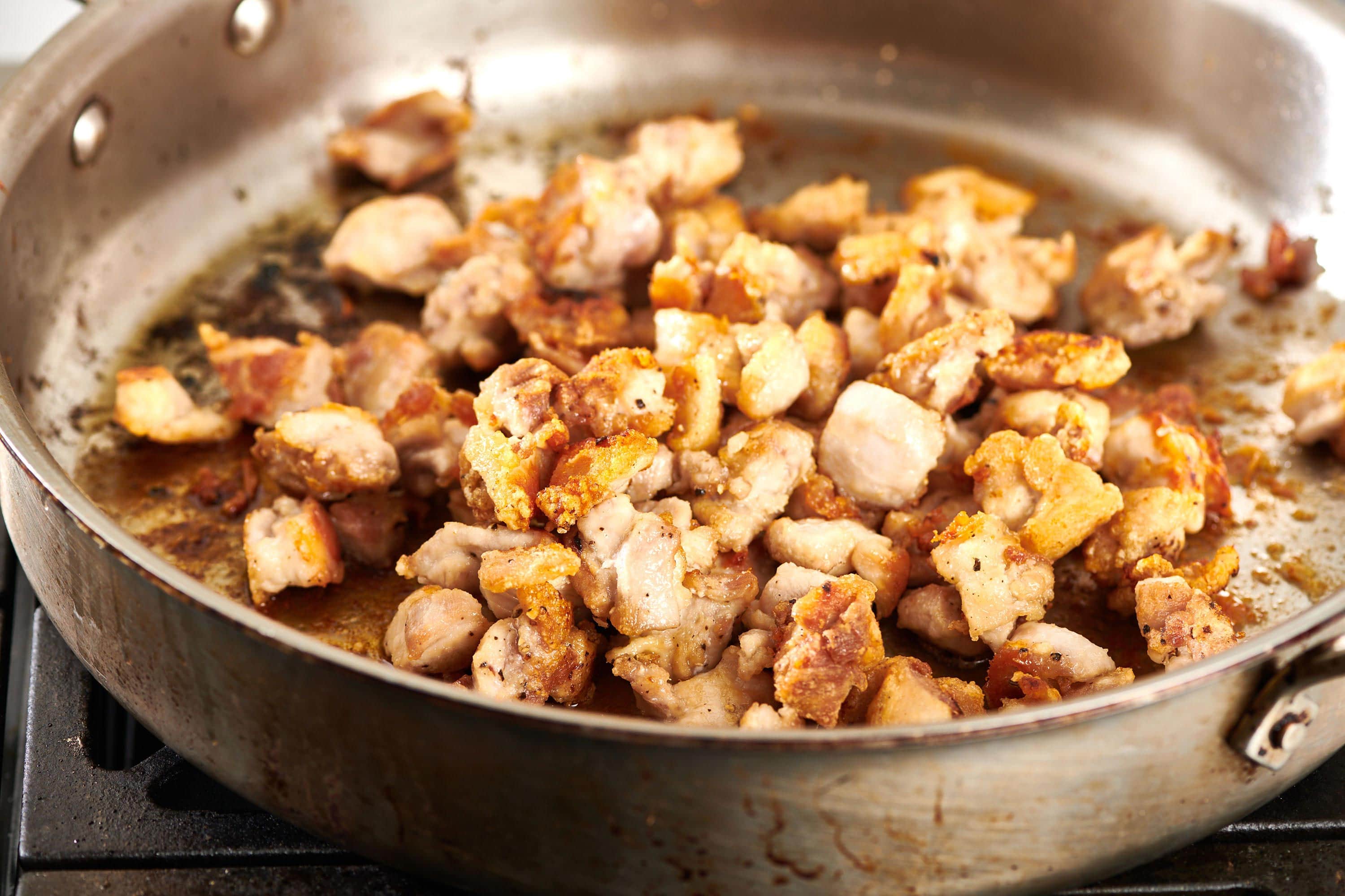 Cubed chicken cooking in pan.