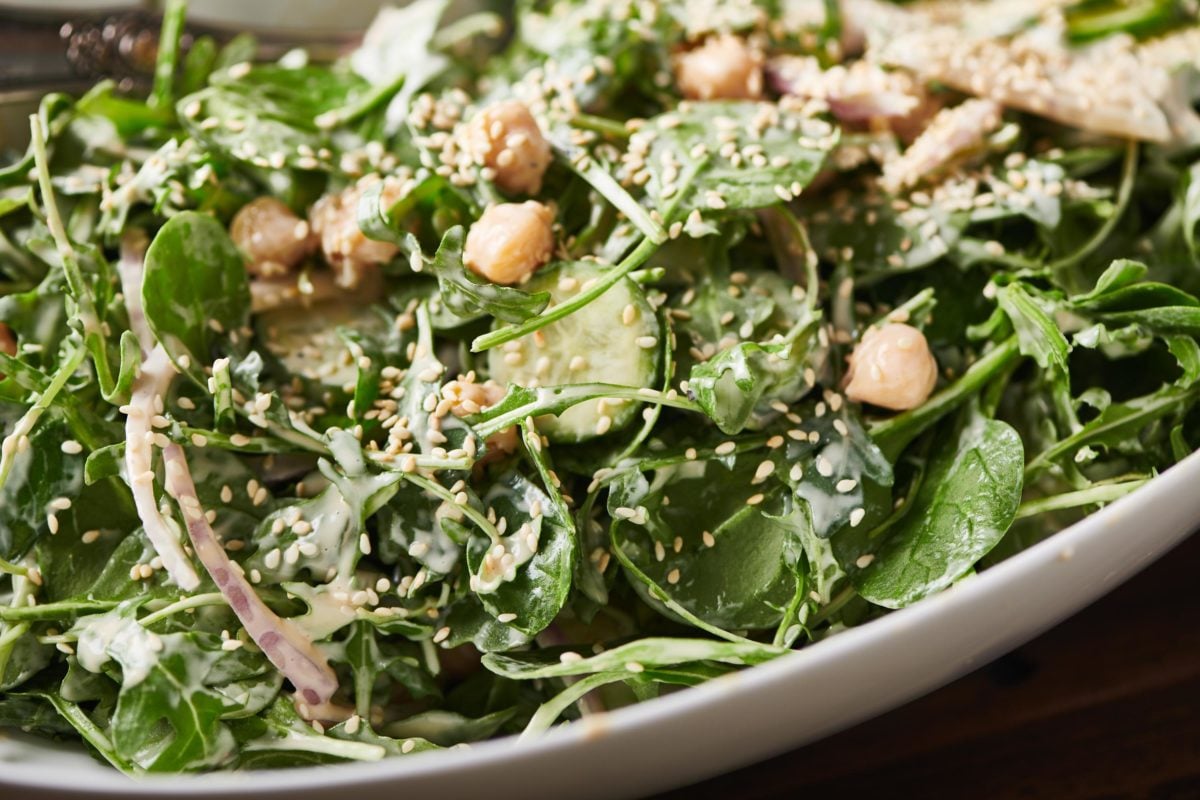 Bowl of Green Salad with Chickpeas and Spicy Honey Tahini Dressing topped with sesame seeds.