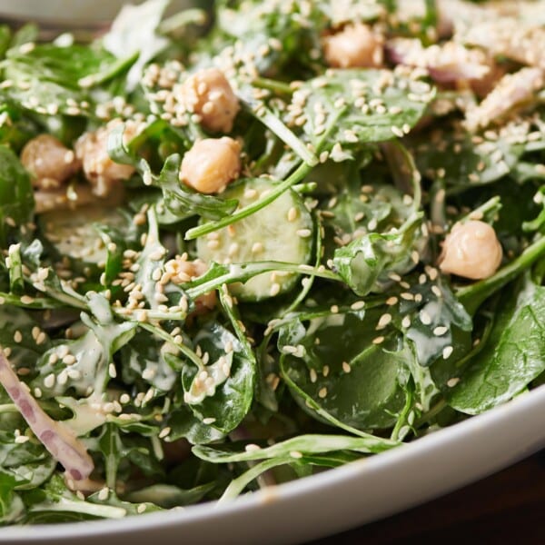 Bowl of Green Salad with Chickpeas and Spicy Honey Tahini Dressing topped with sesame seeds.