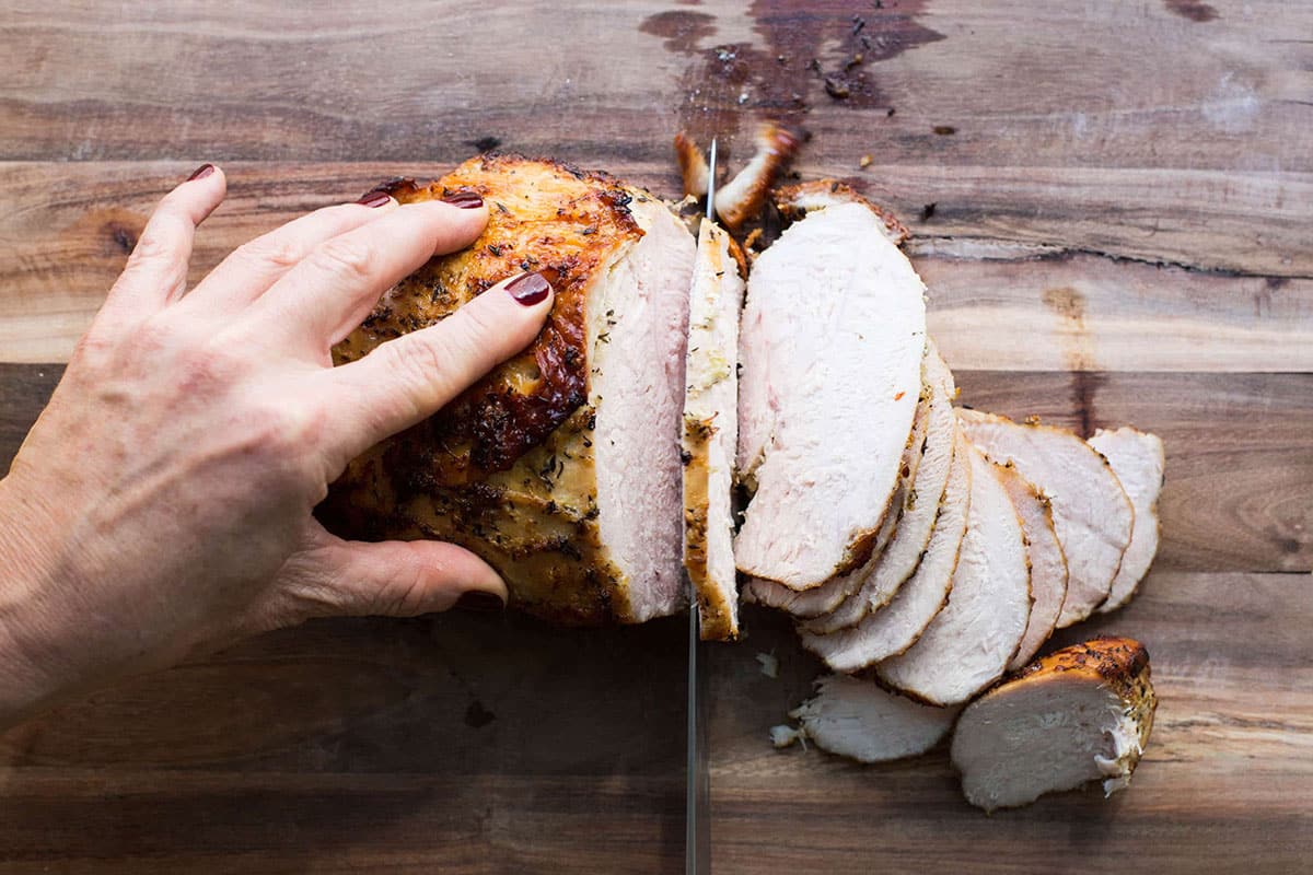 Slicing Lemon-Garlic Roasted Turkey Breast on cutting board.