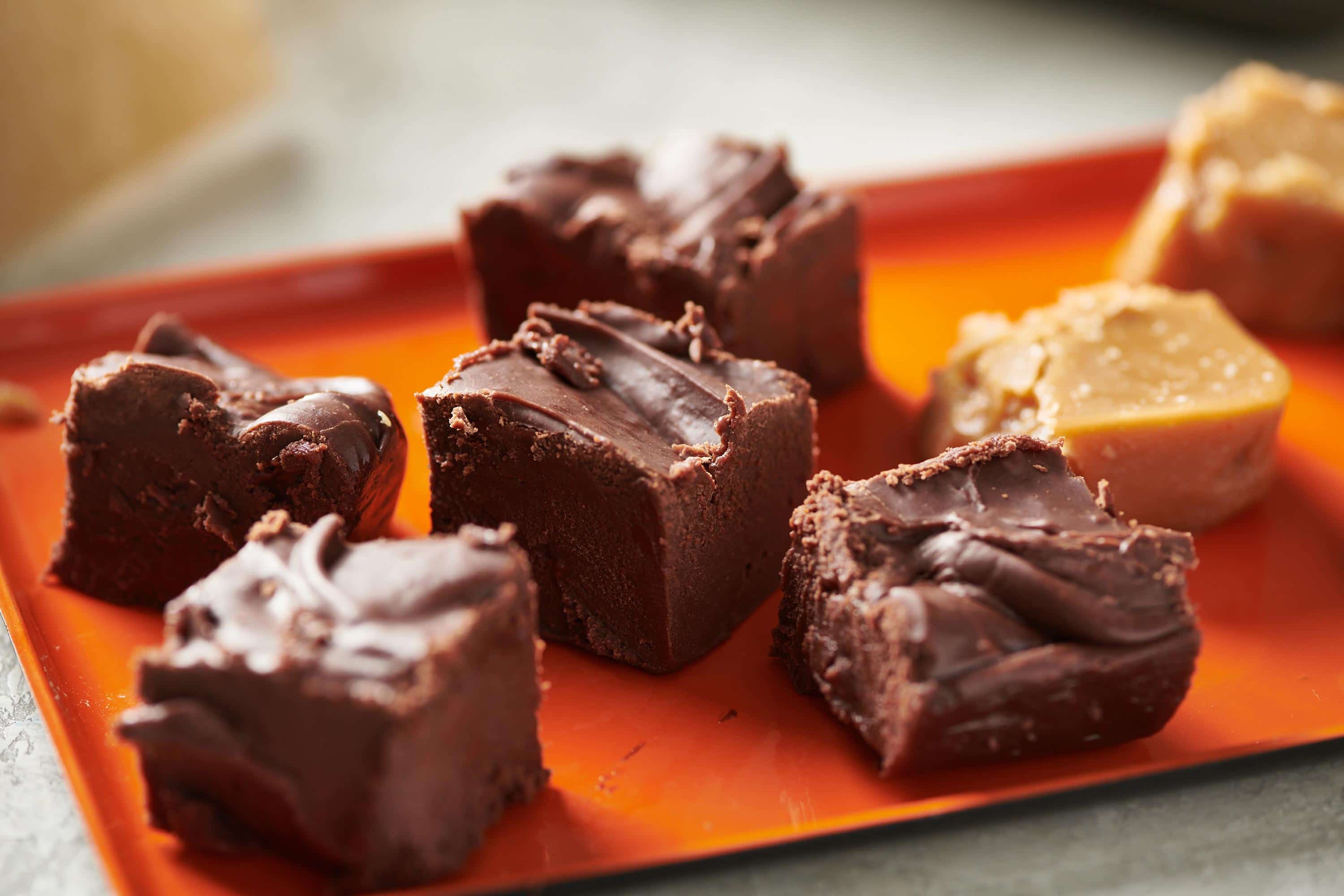 Old-Fashioned Chocolate Fudge in squares on a red serving plate.