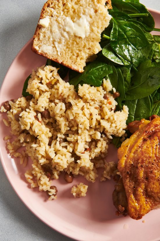 Arroz con Gandules on a plate with bread, spinach, and meat.