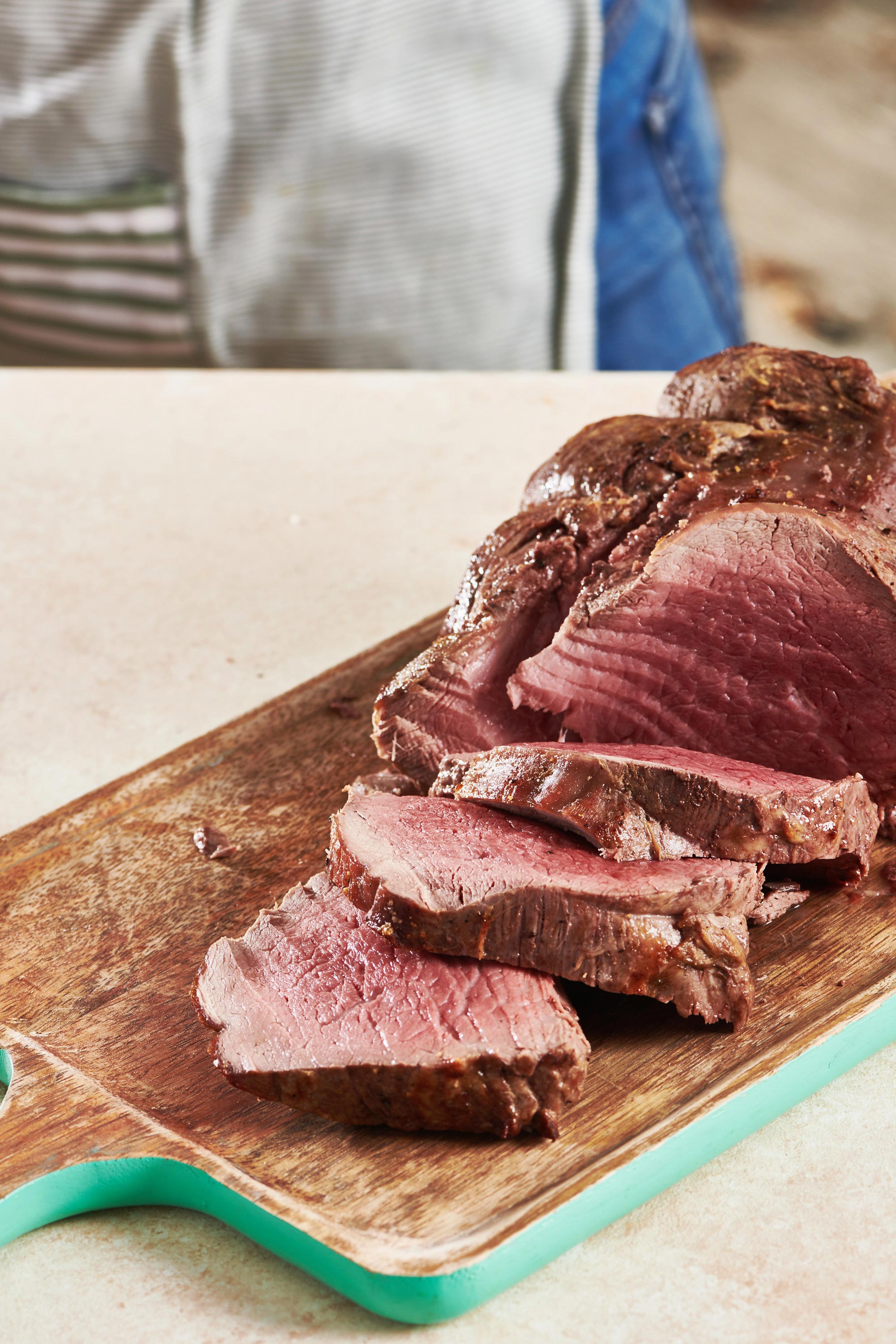 Partially-sliced Beef Tenderloin Roast on a wooden board.