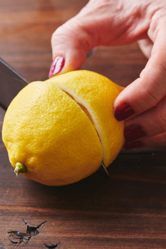 Woman slicing a lemon in half.