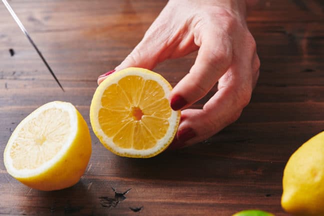 Woman holding half of a lemon.