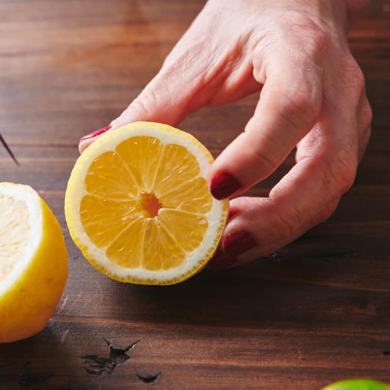 Woman holding half of a lemon.