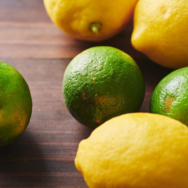 Three lemons and three limes on a wooden surface.