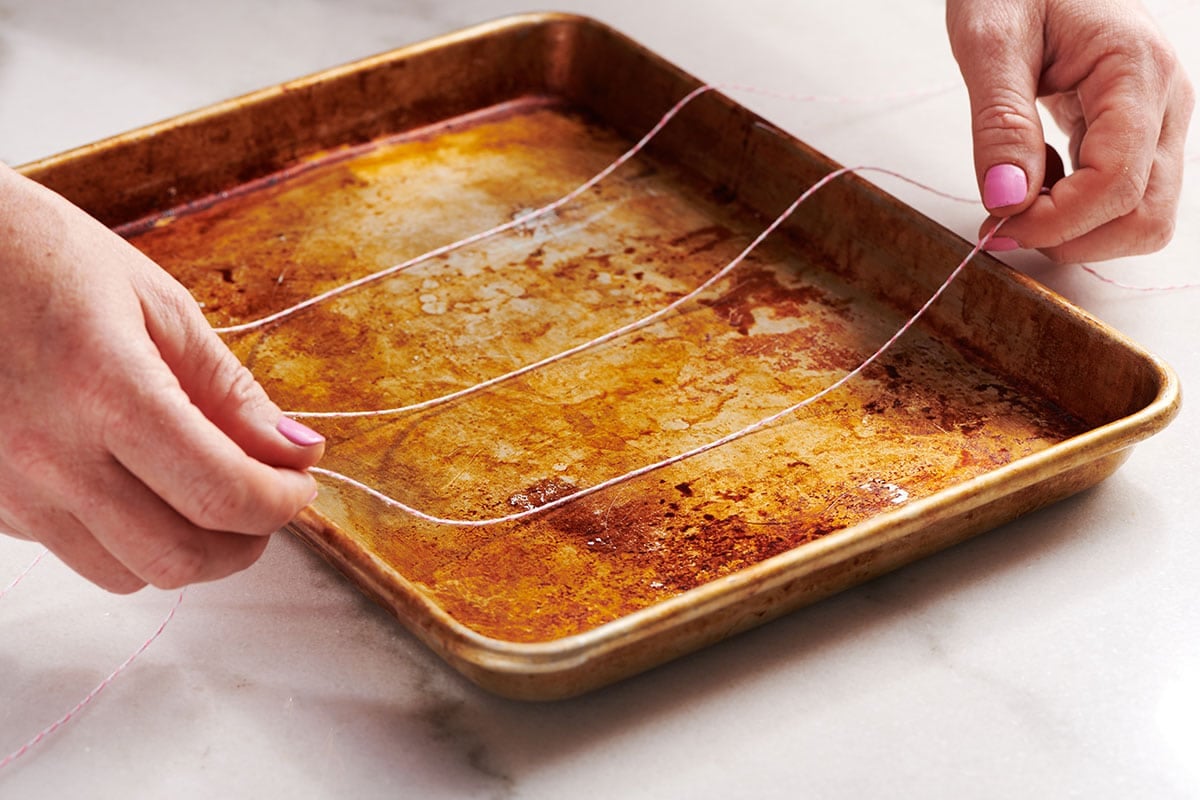 Placing cooking twine on baking sheet.
