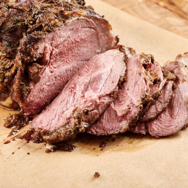 Leg of lamb sliced on cutting board.