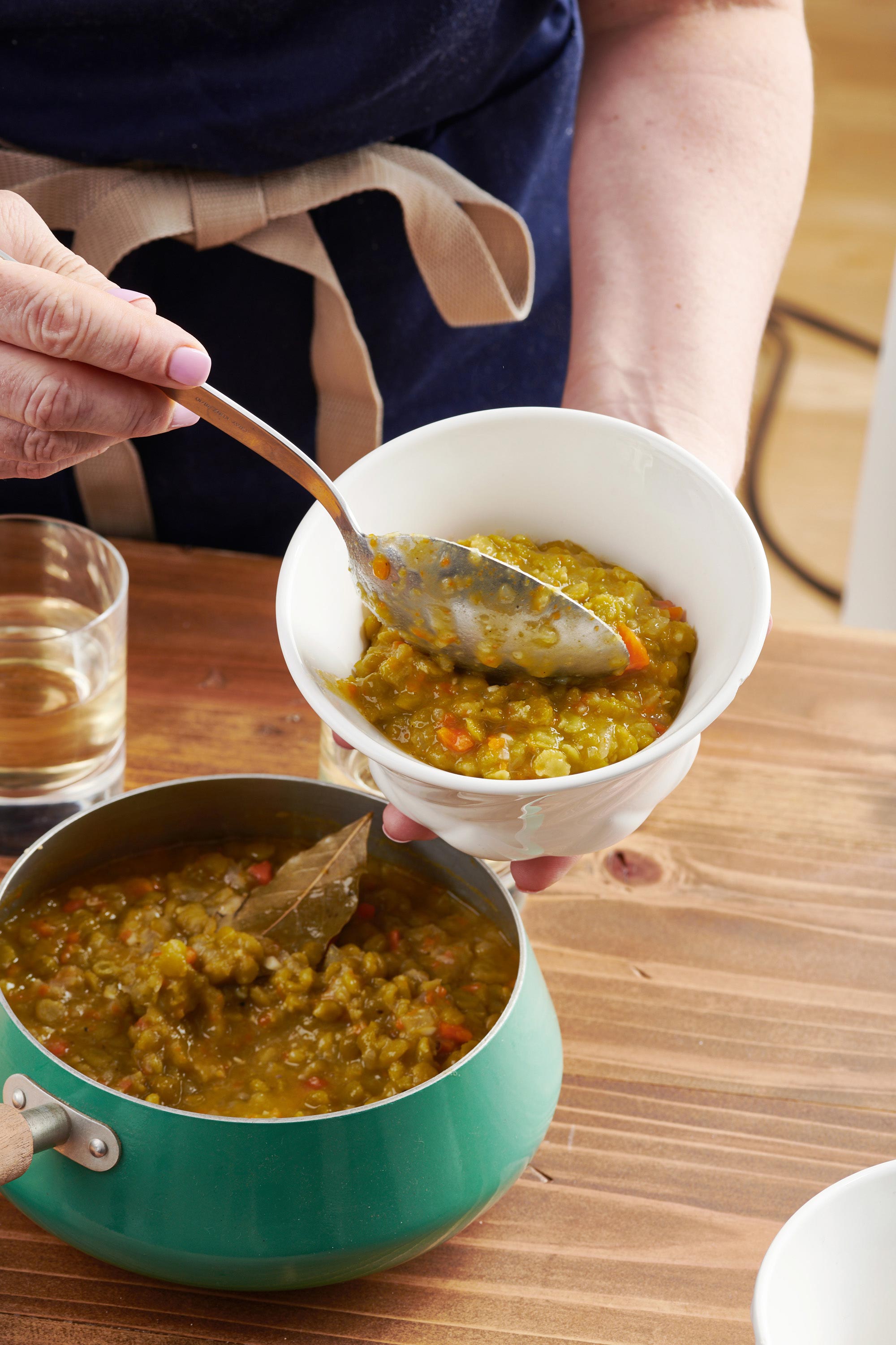 Woman scooping Vegetarian Split Pea Soup into a white bowl.