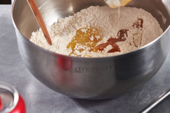 Butter-honey mixture pouring into a bowl of dry ingredients.