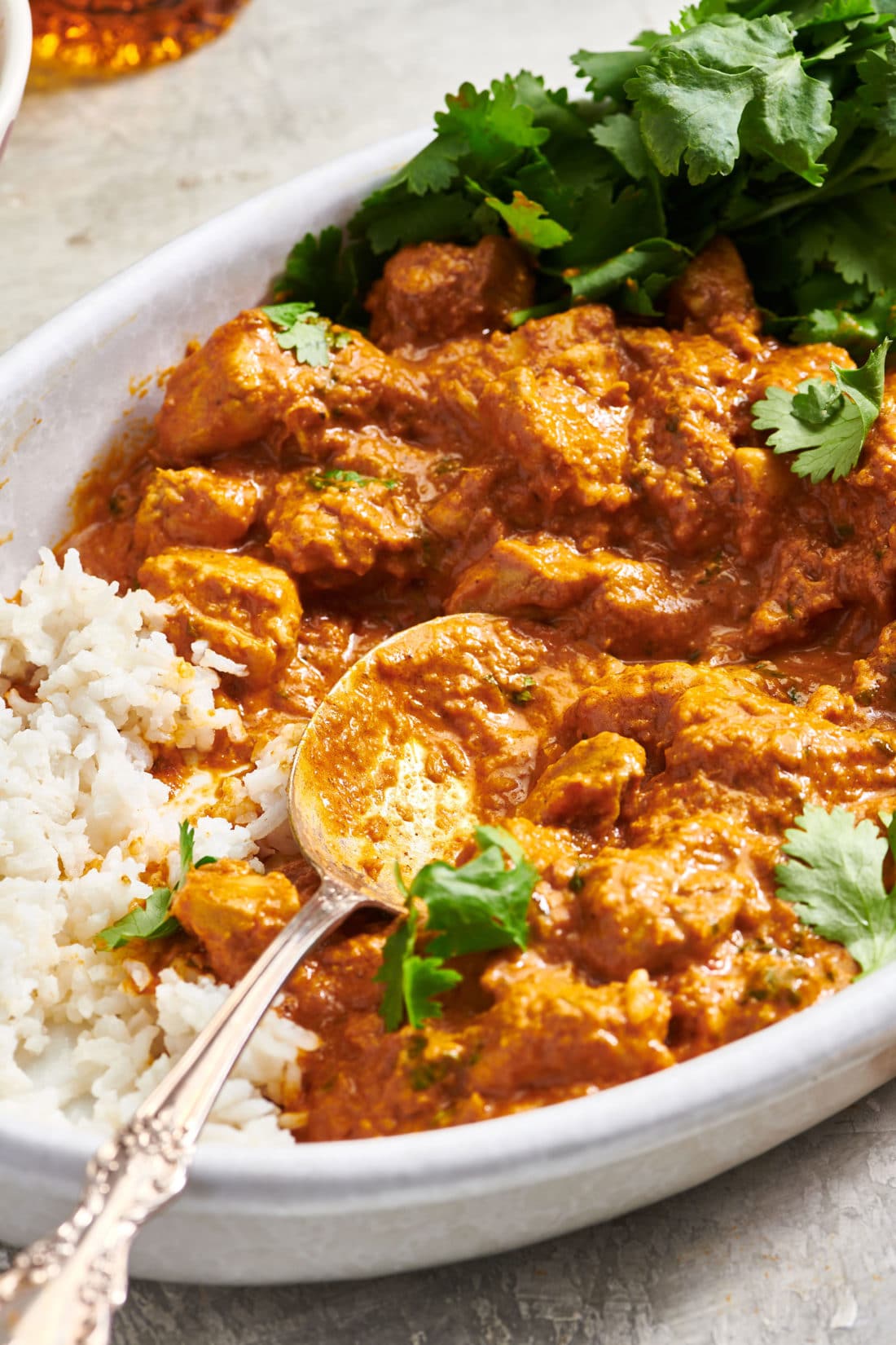 Spoon in a serving dish of Butter Chicken (Murgh Makhani).