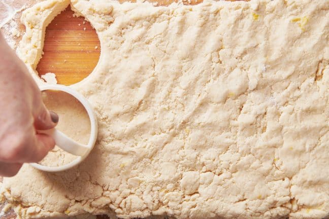Woman cutting circles out of shortcake biscuit dough.