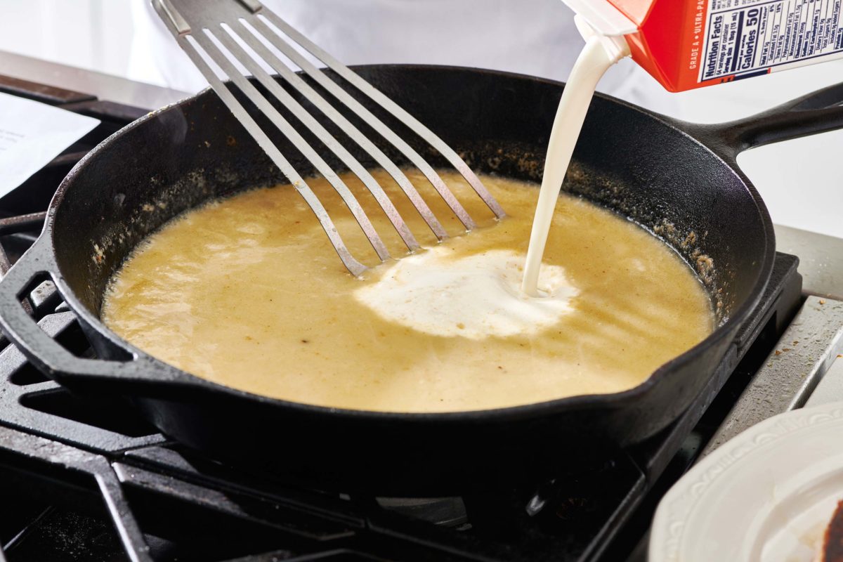 Cream pouring into a skillet with a flour and broth mixture.