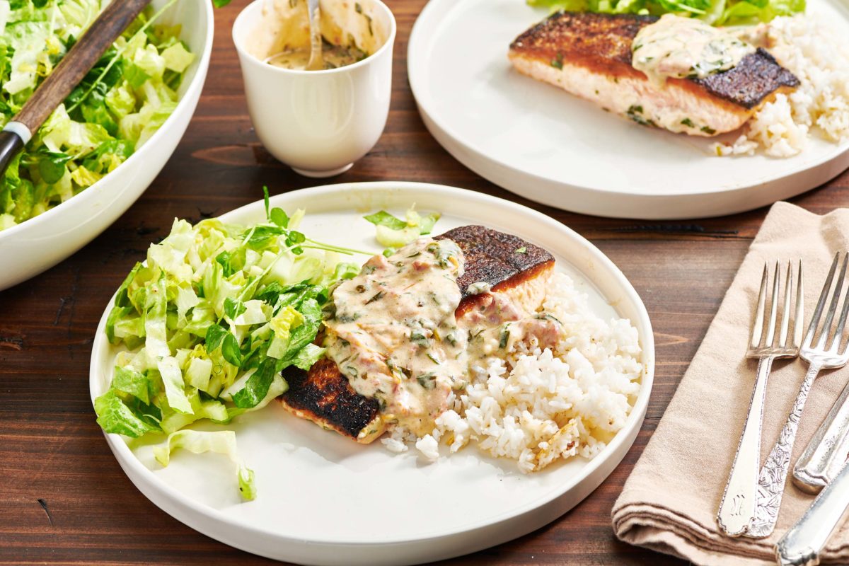 Creamy Tuscan Salmon, rice, and salad on plates.